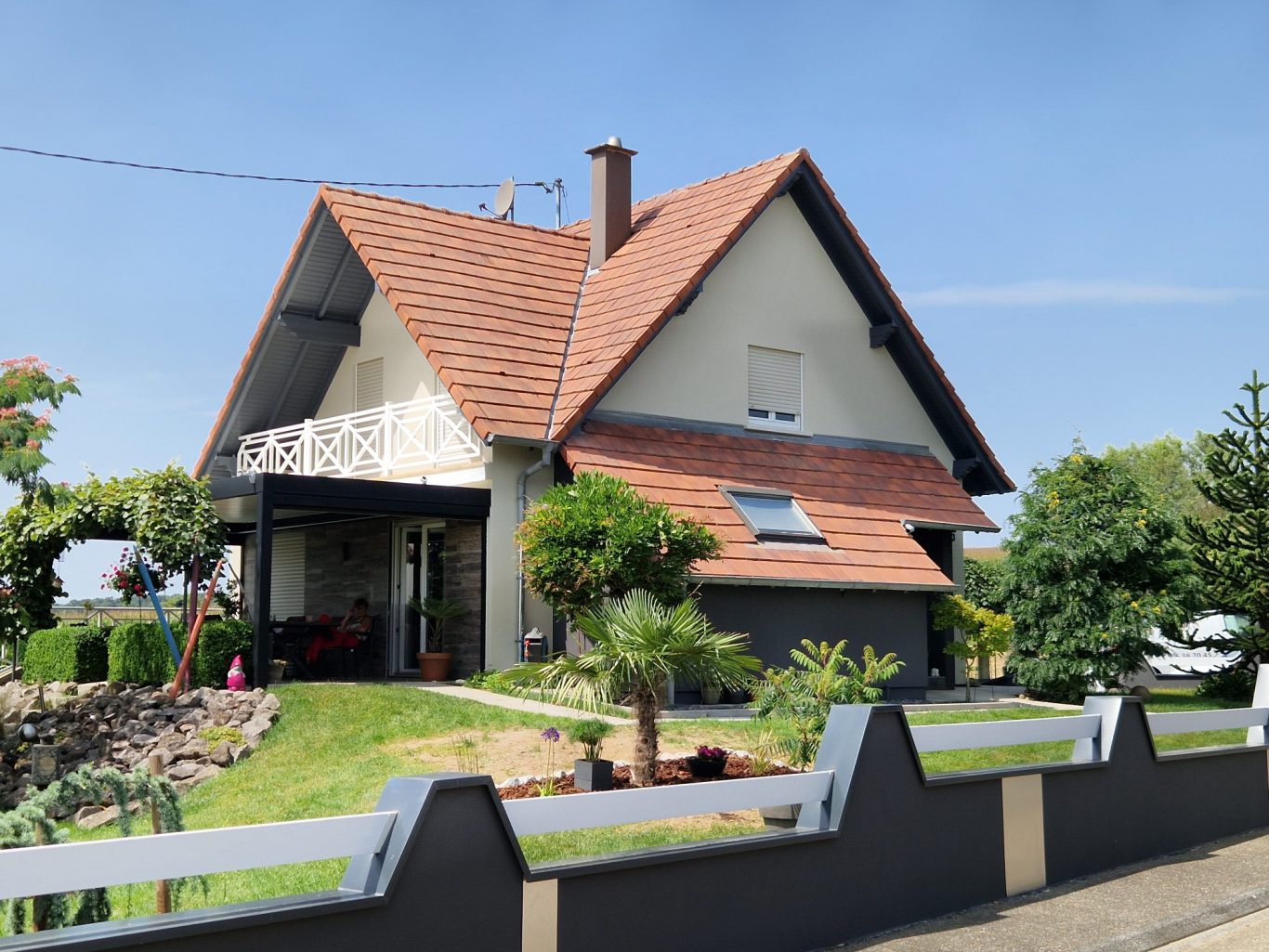 Après - Facade moderne Maison à étage avec un toit en pente, jardin bien entretenu et balcon.