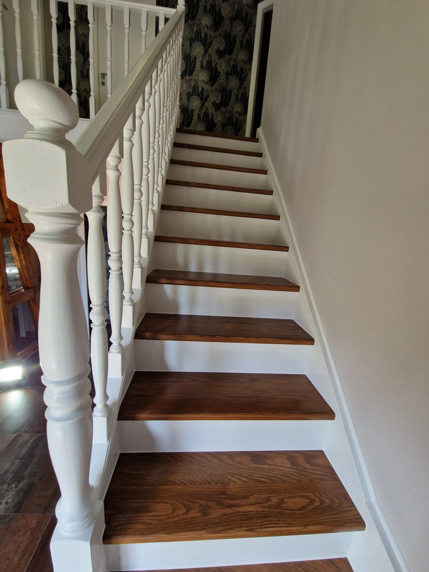 Après - Escalier classique Escalier en bois clair avec rampe blanche, menant à un couloir.