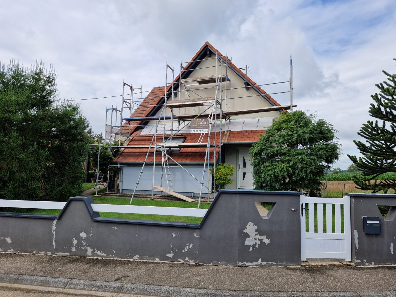 Avant - Facade moderne Maison en rénovation, échafaudages autour, ciel nuageux.