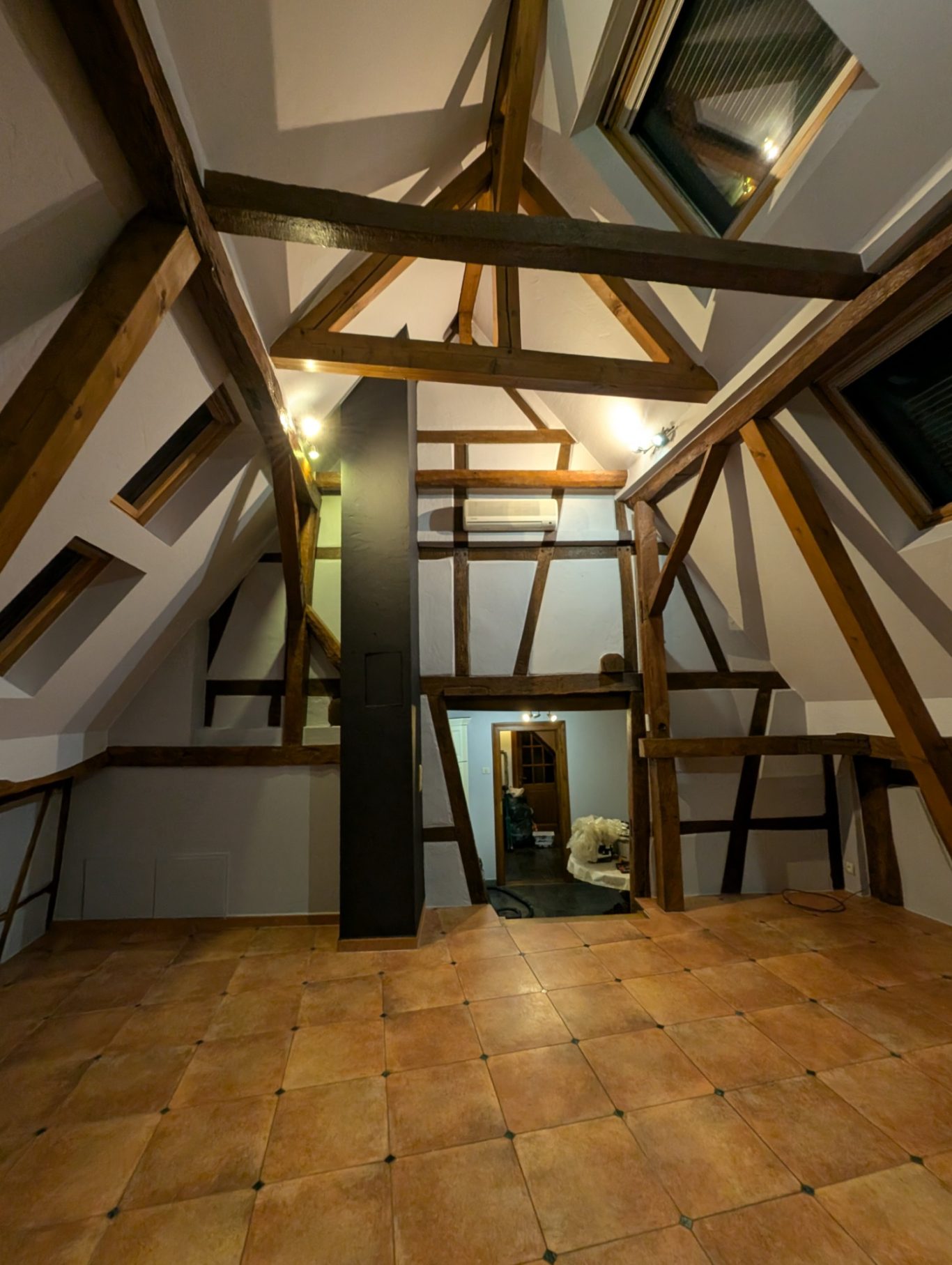 Aprés - Grande chambre colombage Intérieur d'une pièce sous pente avec des poutres en bois et des fenêtres de toit.